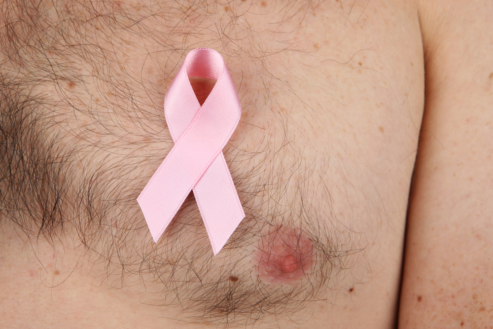A hairy man's chest with a pink breast cancer ribbon pinned to it in support of breast cancer.